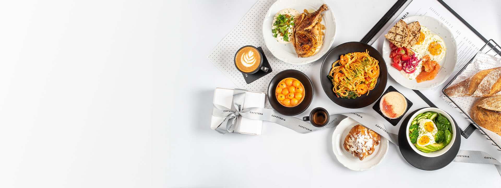 A table with various dishes including pasta, eggs with avocado, smoked salmon, pastries, fruit, and cups of coffee and espresso.