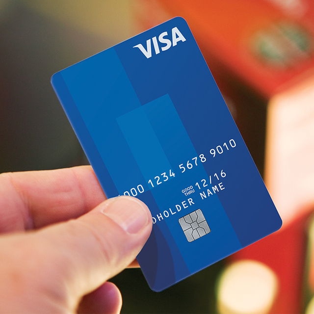Close up of blue Visa Card being held up by a person.