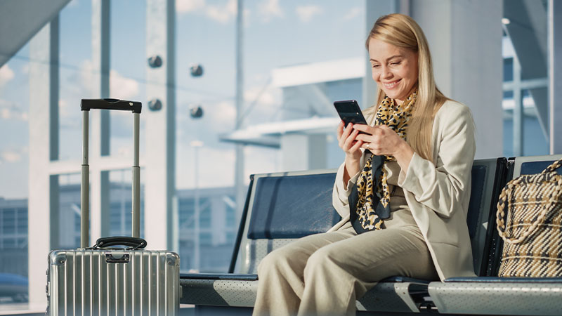 A woman holds a phone with a Visa payment app in a lively sports bar, surrounded by cheering fans watching a soccer match on TV.