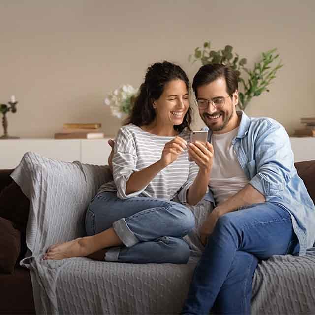 A man and a woman sitting on the sofa with a smartphone 