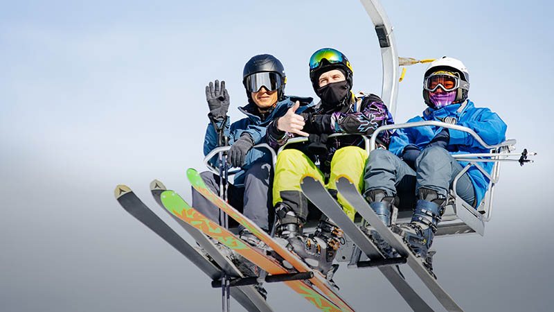 Three skiers elevating on the ski lift