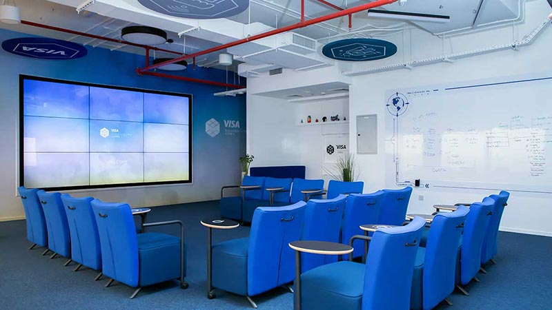 A meeting room at the Dubai innovation center that includes a monitor wall and a white board.